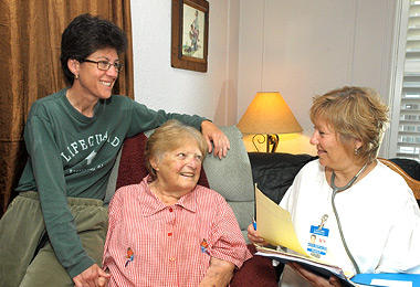 Professional caregiver assisting elderly client in their home living room